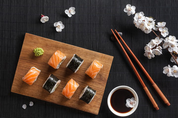Set of sushi and maki rolls with branch of white flowers on stone table