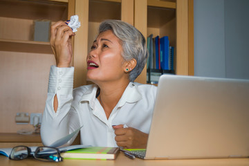 Attractive desperate and stressed middle aged Asian woman screaming gesturing overwhelmed and...