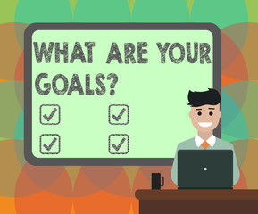 Word writing text What Are Your Goals. Business concept for Tell us your objectives what you want to accomplish Blank Bordered Board behind Man Sitting Smiling with Laptop Mug on Desk