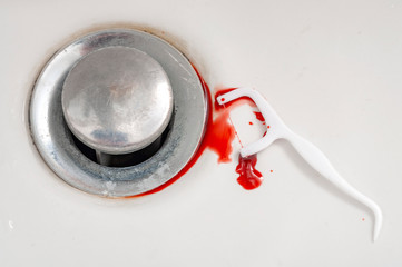 Bleeding gums when flossing and gingivitis concept theme with close up on a dental floss pick covered in blood and doped in a bathroom sink