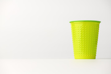 A plastic disposable Cup stands on the right on a white background. Isolated background.Cup with pimples.