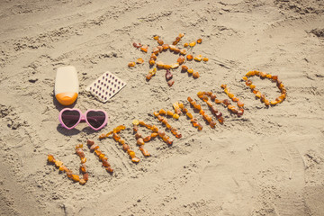 Medical pills, inscription vitamin D and accessories for sunbathing on sand at beach