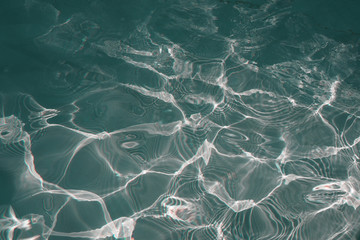 Rippled pattern of clean water in a green swimming pool for background