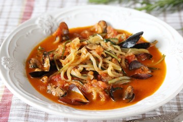 zucchini spaghetti with mussels in tomato sauce in a beautiful bright plate. keto pasta. Low-Carb