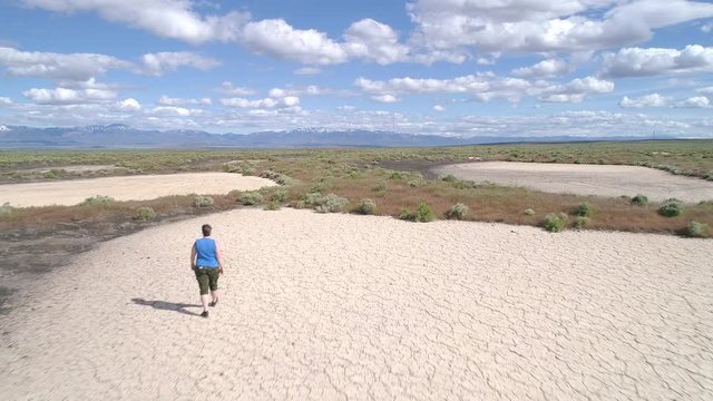 Flying past truck and woman walking through the dry desert in vast open landscape in Utah.