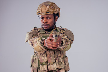 american man in camouflage suit aiming with a pistol studio shot