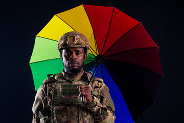 military army african male warrior camouflage suit sorrow sadness wrapped in an American flag standing under a rainbow umbrella black background studio ,lying violence news criminal media