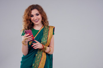 beautiful and young indian business woman in traditional india sari working using a smartphone phone.asian student girl remote work freelancer