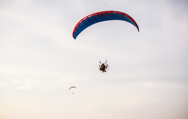 Adventure man active extreme sport pilot flying in sky with paramotor engine glider parachute. Paramotor flying on the sky at sunset. 