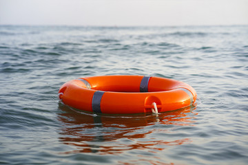Red lifebuoy in sea on water. Life ring floating on top of water. Life ring in ocean.