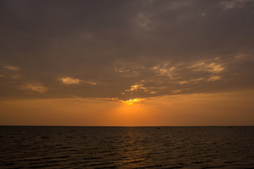 Bright sunset with large yellow sun under the sea surface. sunrise in the sea. Beautiful sunset above the sea. Tropical sunset on the beach.