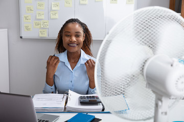 Businesswoman Enjoying Breeze With Electric Fan