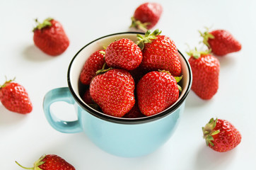 ripe strawberries in a blue cup on a white background
