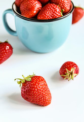 ripe strawberries in a blue cup on a white background