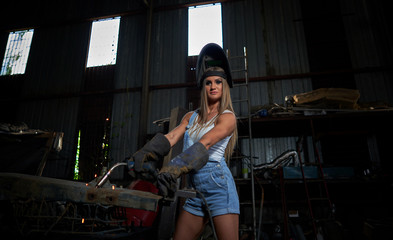 Fototapeta na wymiar sexy girl in overalls with working tools in a big hangar