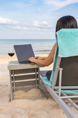 Woman typing on laptop by the beach