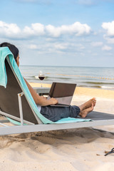 Young woman freelancer working with laptop on tropical beach