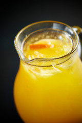 Orange juice in pitcher on black background