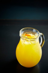 Orange juice in pitcher on black background