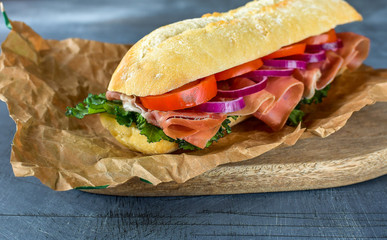 sandwich from a cereal baguette , ham, lettuce, kale on a gray background. takeaway sandwich,