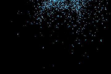 Blue falling particles round shape on black backround.