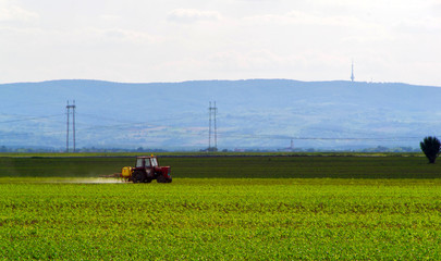 Fototapeta na wymiar Farming tractor plowing and spraying on field