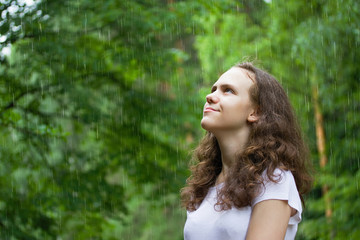 young girl under the rain in a summer park