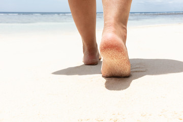 Woman's Feet Walking On Sandy Beach