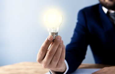 businessman in the office holds a shining lamp, the symbol of the idea; business concept