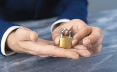 young businessman holding padlock in his hands; security; business concept