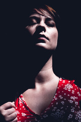Sensual young woman with closed eyes in darkness
