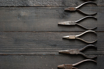 old pliers on black wood background directly above