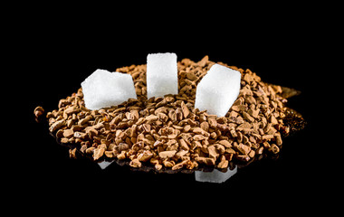 Heap of instant coffee with sugar cubes on black.
