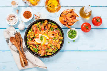 Traditional spanish seafood paella in the fry pan on a blue wooden  table, top view.