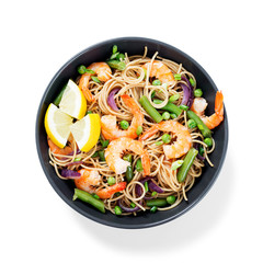Stir fry noodles with shrimps and vegetables in black bowl isolated on white background.