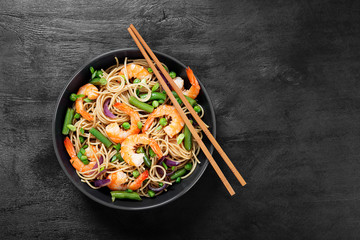 Stir fry noodles with shrimps and vegetables in black bowl.