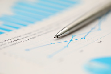 Silver pen lying down at important statistic document at empty working table