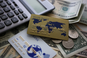 Credit card and calculator lying on big amount of US money