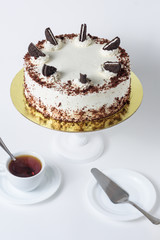 Fototapeta premium Cake with chocolate cookies and a cup of tea on a white background