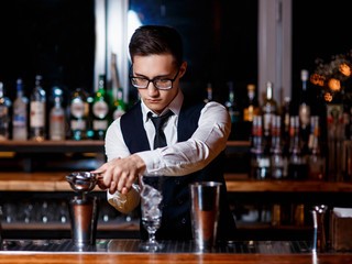 barman at work. A young bartender works with a shaker. Prepares delicious alcoholic cocktails
