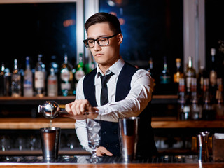 barman at work. A young bartender works with a shaker. Prepares delicious alcoholic cocktails