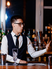 barman at work. A young bartender works with a shaker. Prepares delicious alcoholic cocktails
