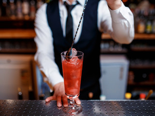 The bartender prepares a delicious orange cocktail with citrus. bartender at work