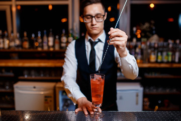 The bartender prepares a delicious orange cocktail with citrus. bartender at work