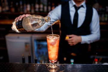 The bartender prepares a delicious orange cocktail with citrus. bartender at work
