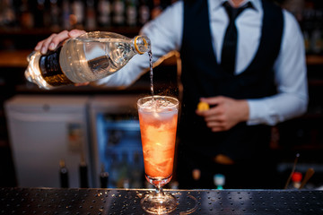 The bartender prepares a delicious orange cocktail with citrus. bartender at work