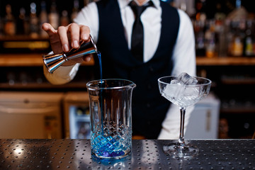 The bartender prepares a cool blue lagoon cocktail. Barman at work