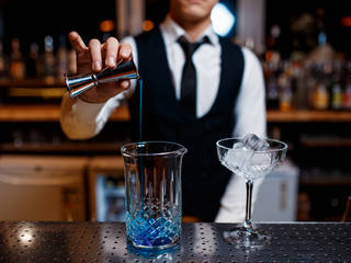 The bartender prepares a cool blue lagoon cocktail. Barman at work
