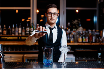 The bartender prepares a cool blue lagoon cocktail. Barman at work