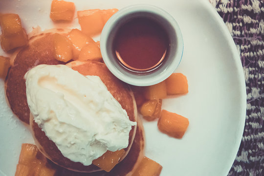 Breakfast pancakes on a plate with mango and sweet sauce. Picture style vintage.